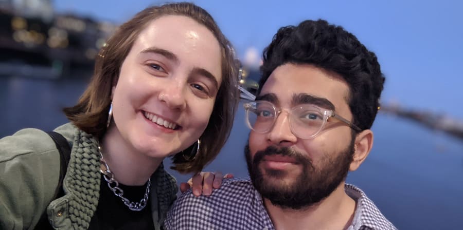 Hannah and her boyfriend stand in front of the sea.