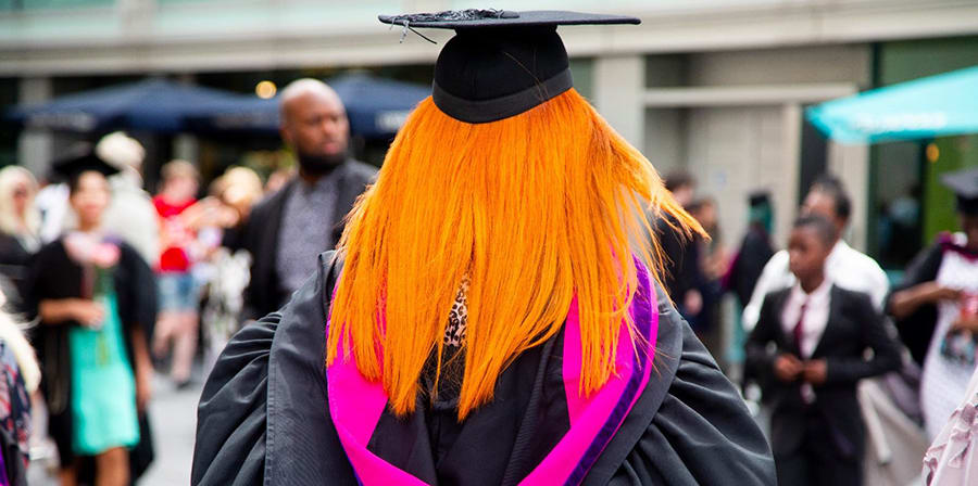 Student in full graduation robes walking towards the Royal Festival Hall