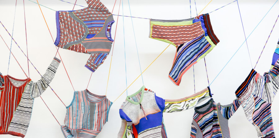 Fashion knitwear installation with garments hanging from the sealing on strings.
