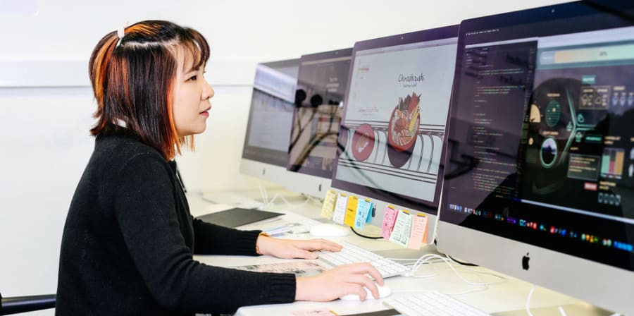 Student working on her designs on computer. Decorative image only.
