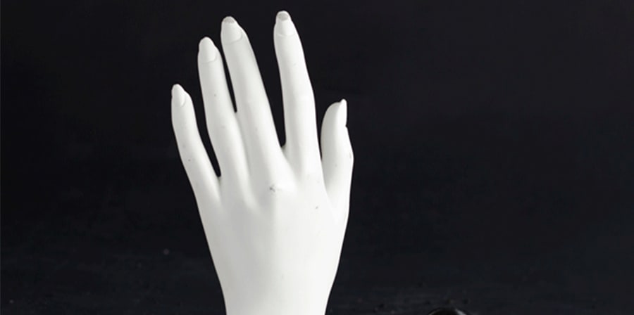 Mannequin hand peaking out of black sand