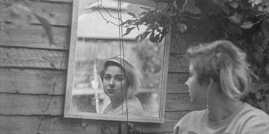 A woman looks at a mirror over her shoulder.