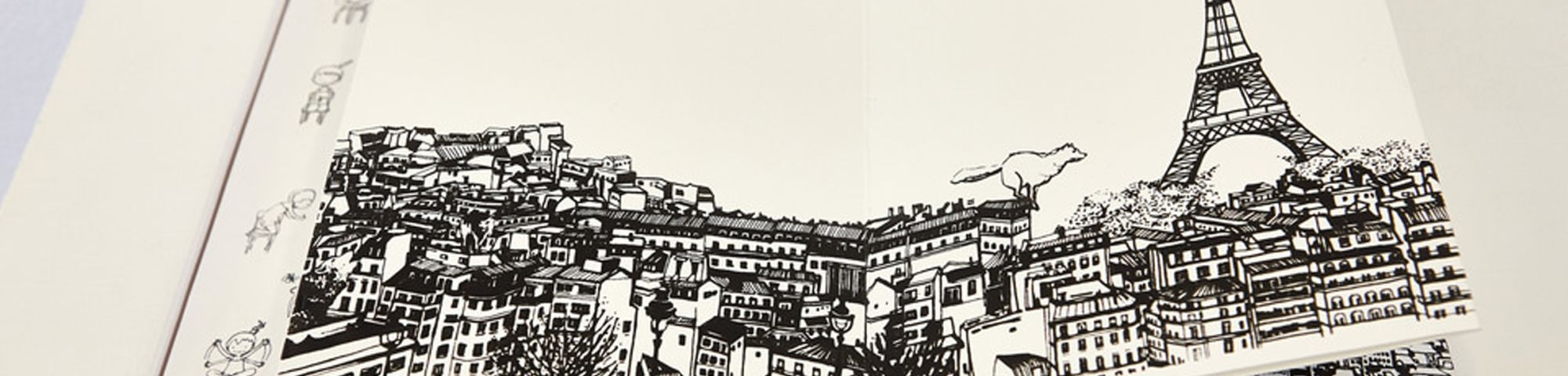 Open sketch book with a black line drawing of the Eiffell Tower and surrounding buildings