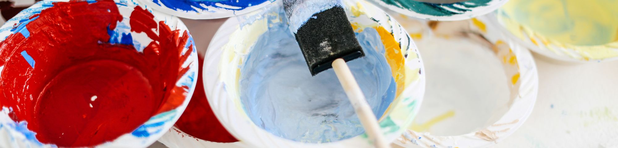 Open paint tins with a paintbrush resting on top