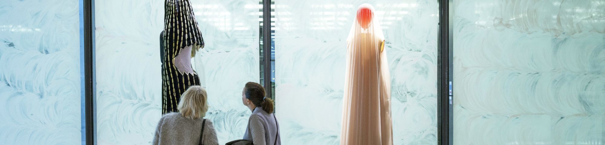 Two people looking at mannequins in a display
