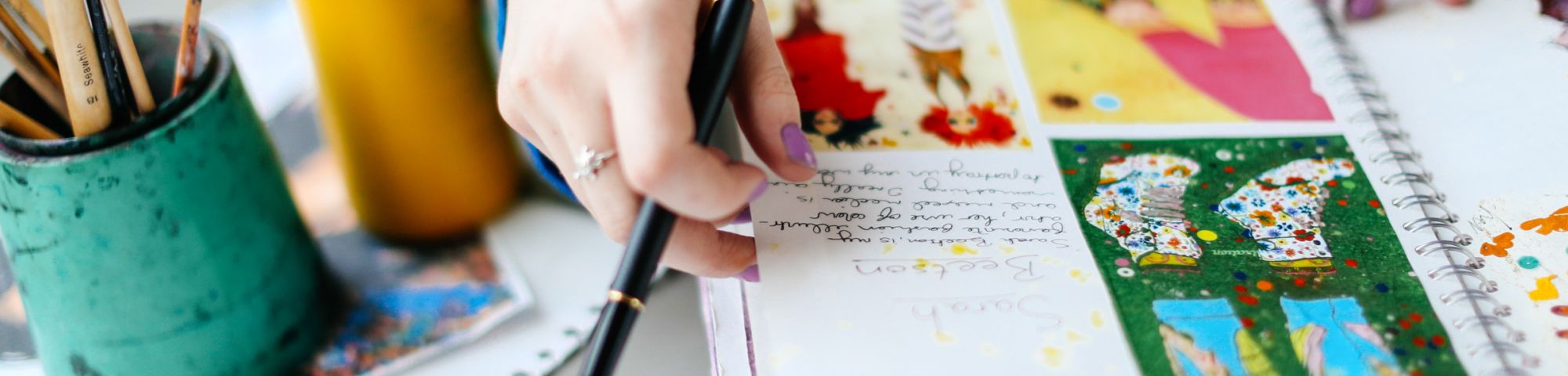 Hands arranging illustration pieces and a pot of pencils