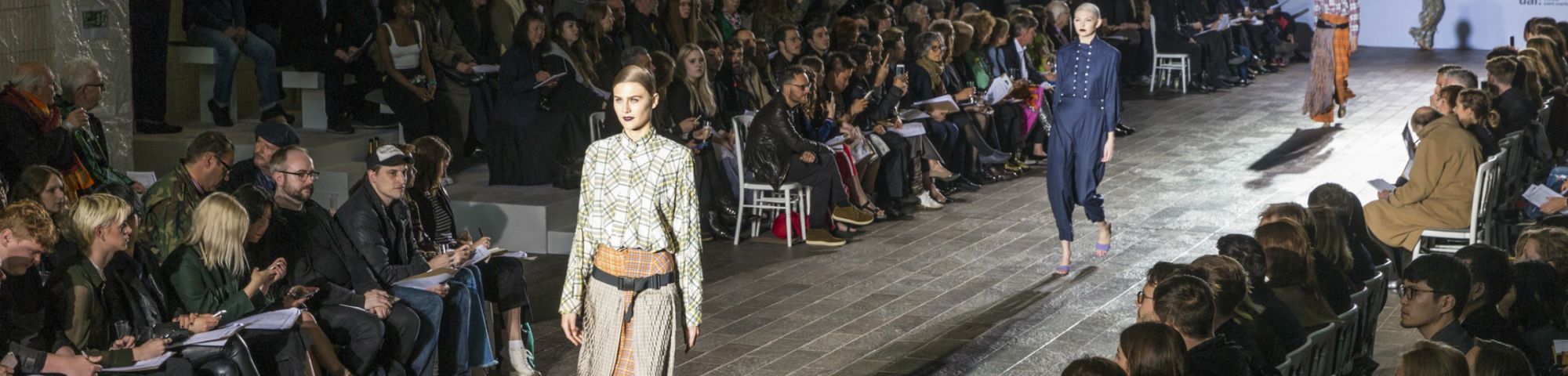 People walking down a fashion catwalk with crowds either side