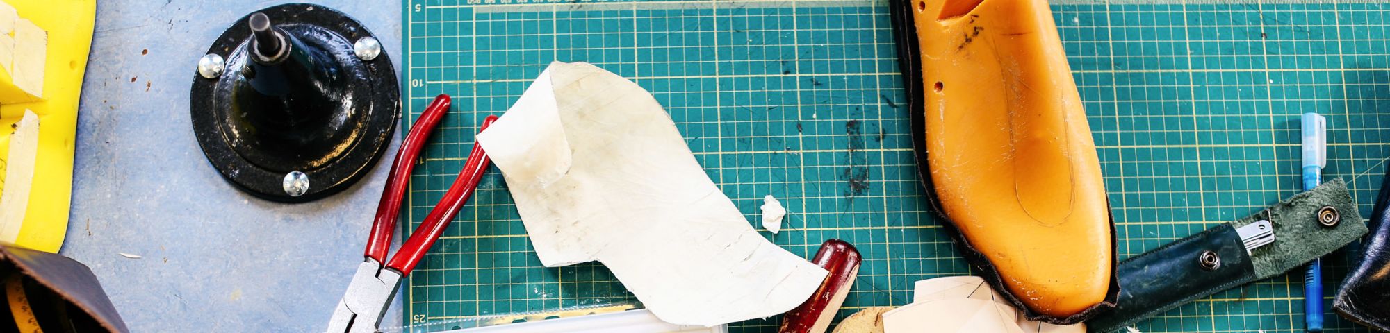 Close up shot of a workbench with pieces of shoes and tools on it