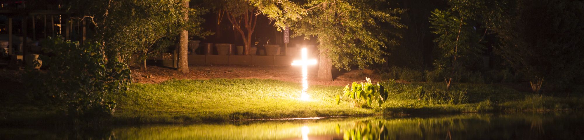 a cross on fire reflected on a lake