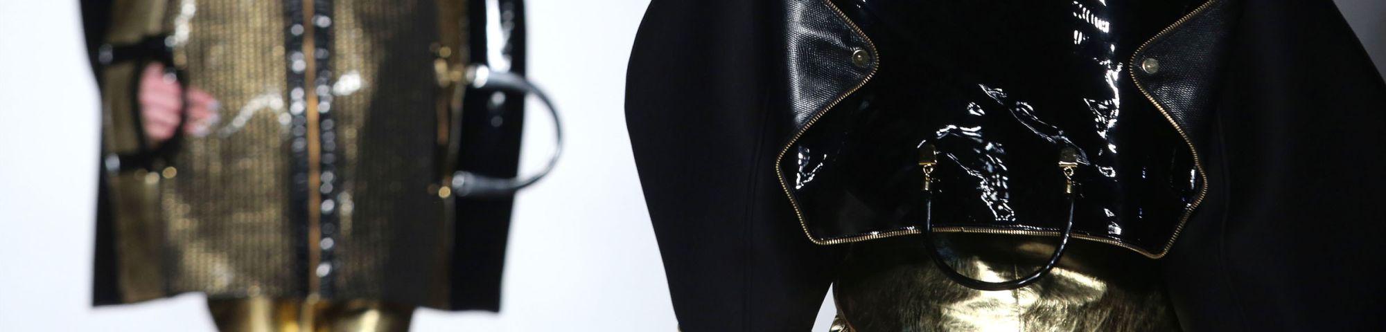 Close up of two people in black and gold clothing on a catwalk