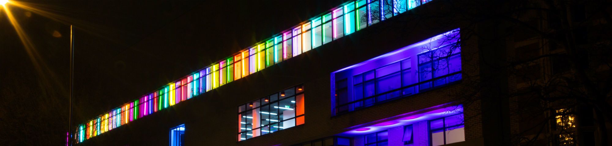 A landscape picture of a building at our Camberwell Campus with multi coloured lights at night.