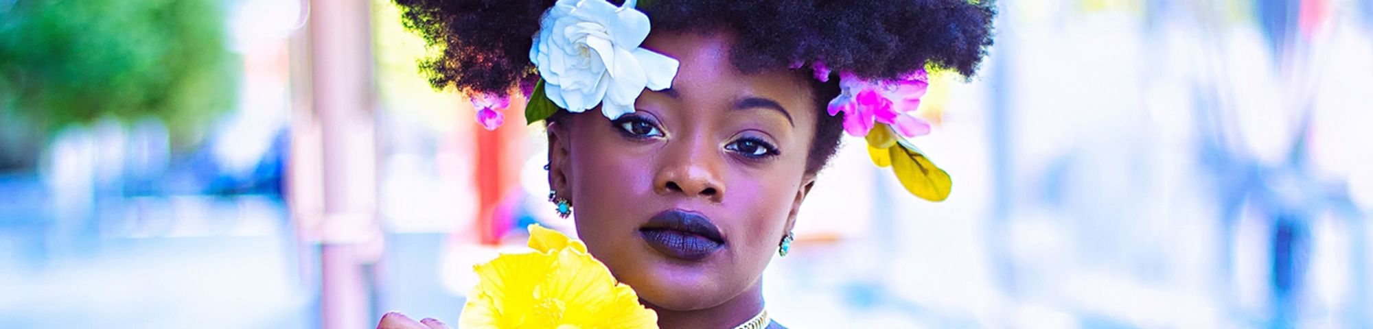 Female model posing with flowers in her hair and denim jacket