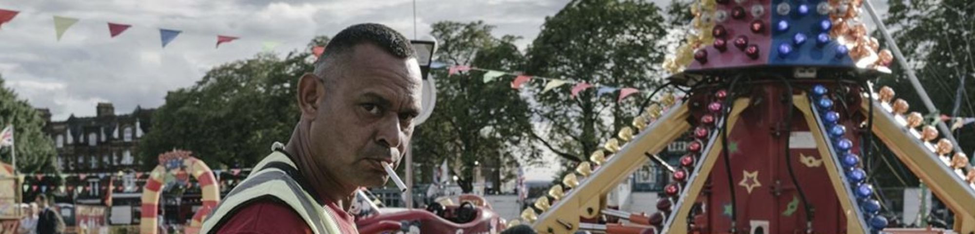 man smoking in front of fairground ride