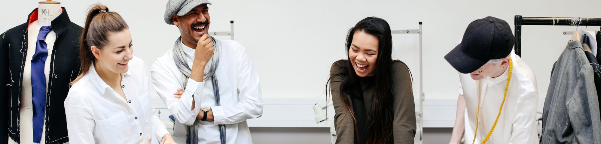 Four laughing people stood around a workbench