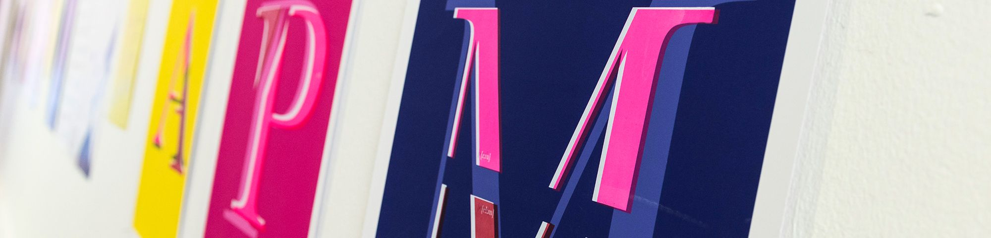 Installation image of graphic screen-printed posters in a range of colours