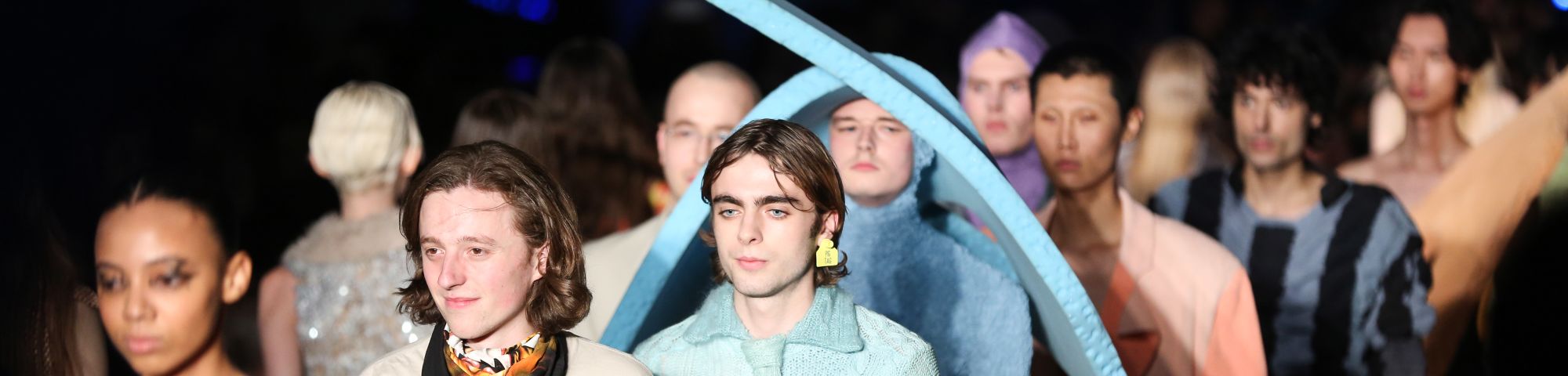 A line of male models walking the catwalk