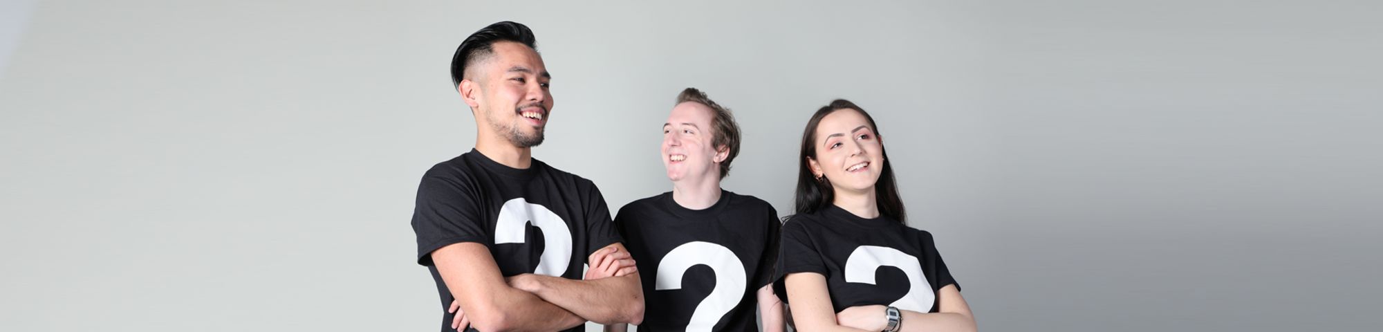 Image of 3 students, 2 male and 1 female wearing black t-shirt with white question marks.