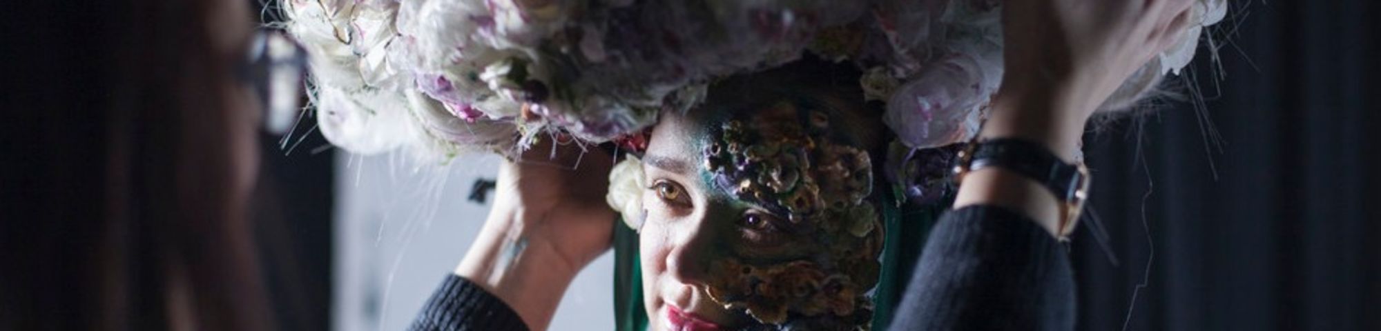 A model having a large floral headpiece adjusted on her head