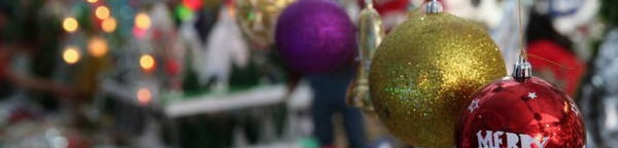 colourful hanging baubles in sharp focus with a background of the Christmas market