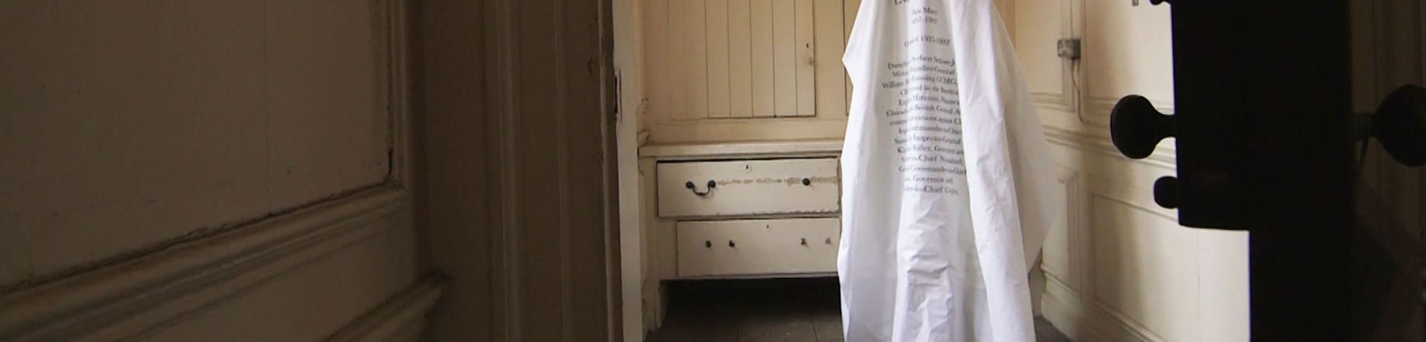 A large piece of material with words written across displayed in an empty room