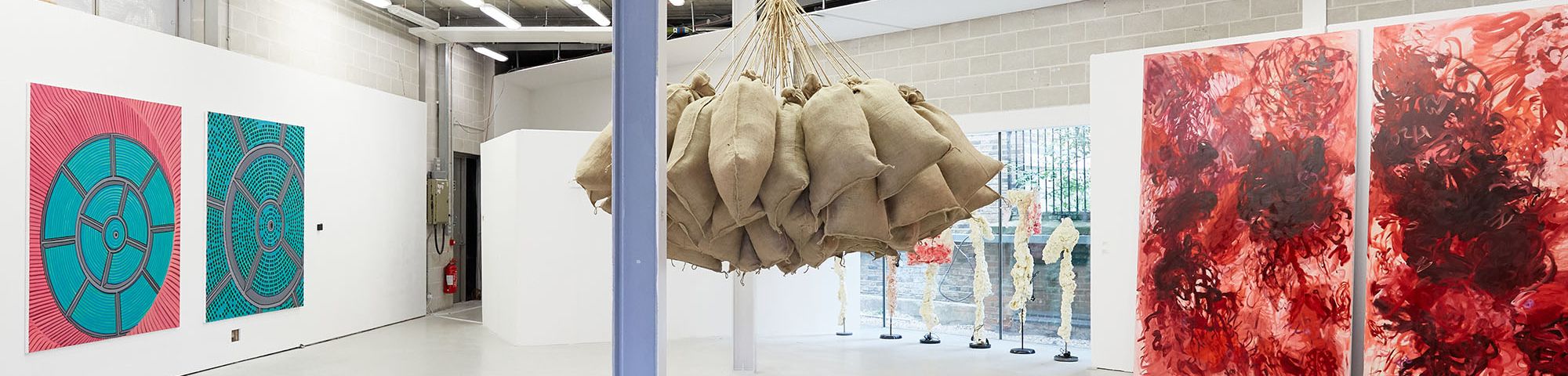 Two sets of paintings and a sculpture of hanging sacks from the ceiling as part of the MA Fine Art Summer Show
