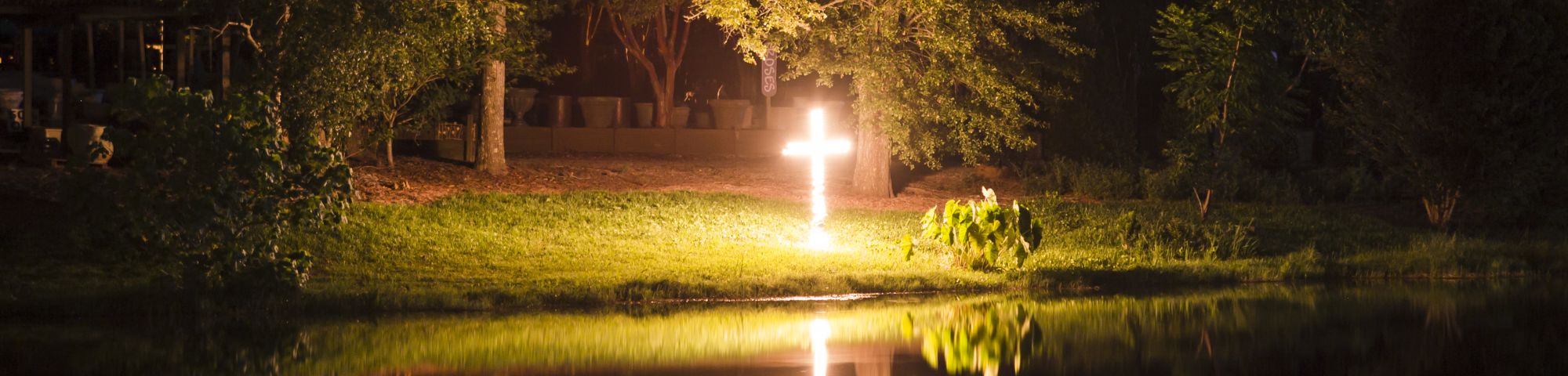 a cross on fire reflected on a lake