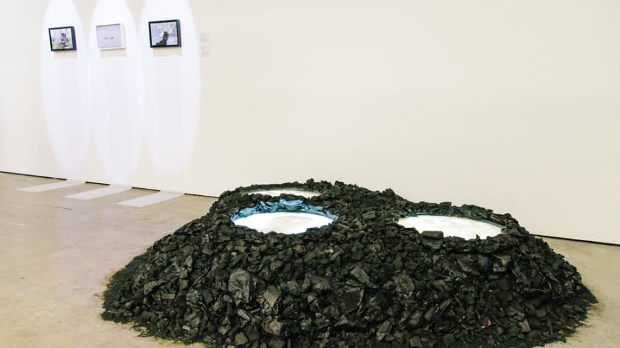 Exhibition space with pictures illuminated on the wall and a large green installation with white light coming out of the top. MA Art and Science, Installation by Caglar Tahiroglu shortlisted for the MullenLowe NOVA Awards, Show 1. © Vic Philips