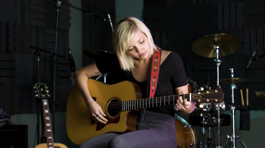 Woman sitting on a stool playing guitar