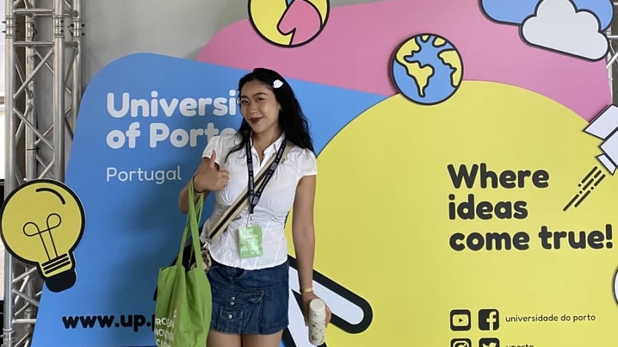 Student standing in front of colourful 'University of Porto' banner while participating in summer school opportunity
