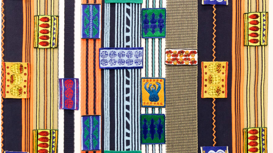 Painting and textile installation featuring multi-coloured patterns in blues, blacks, greens, oranges, pinks and yellows.