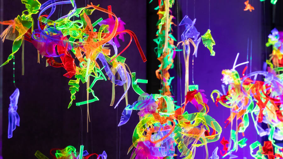Hanging installation made of lots of different coloured neon strips tangled together.