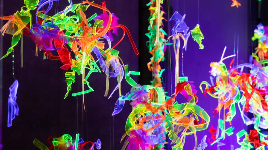 Hanging installation made of lots of different coloured neon strips tangled together.