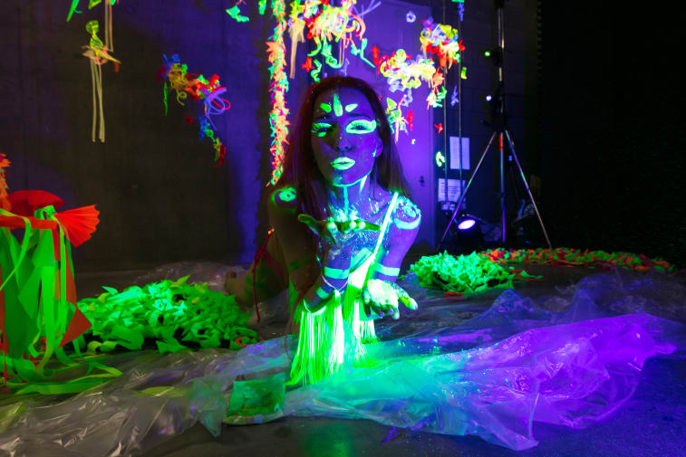 Darkened room with person covered in glow-in-the-dark decoration