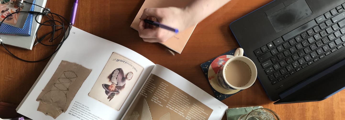 Working from home desk with a laptop, books and coffee