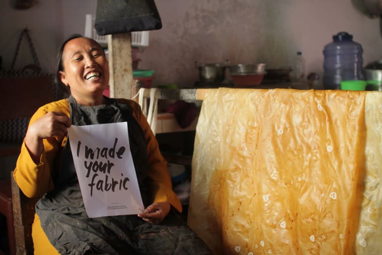A smiling woman holding a sign saying 