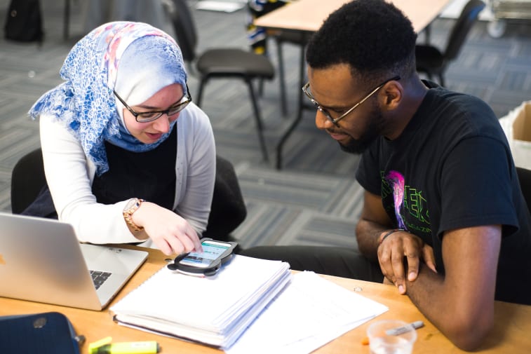 Students looking at app on phone screen.