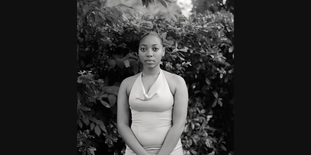 Black and white shot of young woman in prom clothing photographed outdoors near nature 