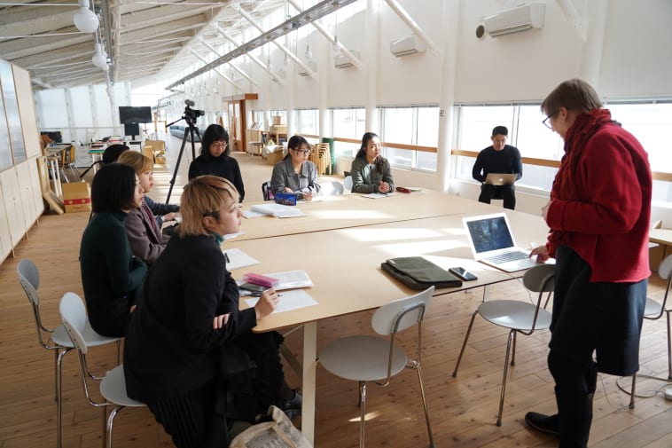Class group around a table with a tutor at the front