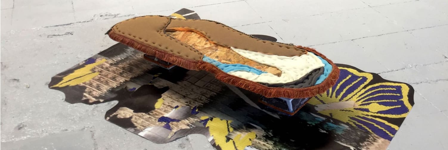 Art sculpture piece made with fabrics of different colours, the piece stands on the floor and has a square shape