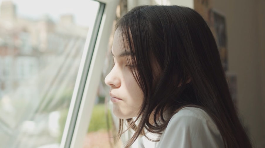 A young girl stares out of the window.