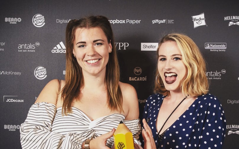 Amy and Georgina smile for a photo with their yellow pencil award