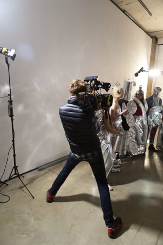 Person holding camera standing in front of people dressed in silver
