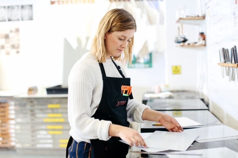 A person working in a studio, it's bright and they are holding some paper