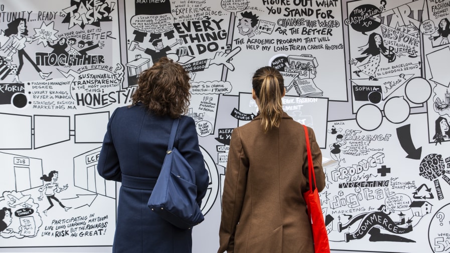 Two people standing up in front of a poster during an exhibition
