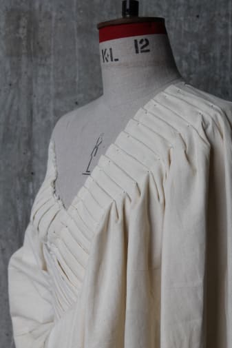 a studio shot of a wide-necked, cream coloured garment on a mannequin