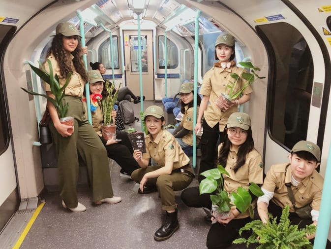 A group of students dressed as park rangers hold otted plants on a tude train
