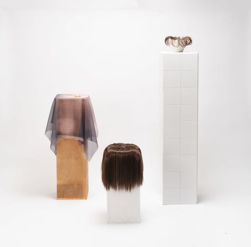 Objects – seemingly made from hair – resting on three plinths