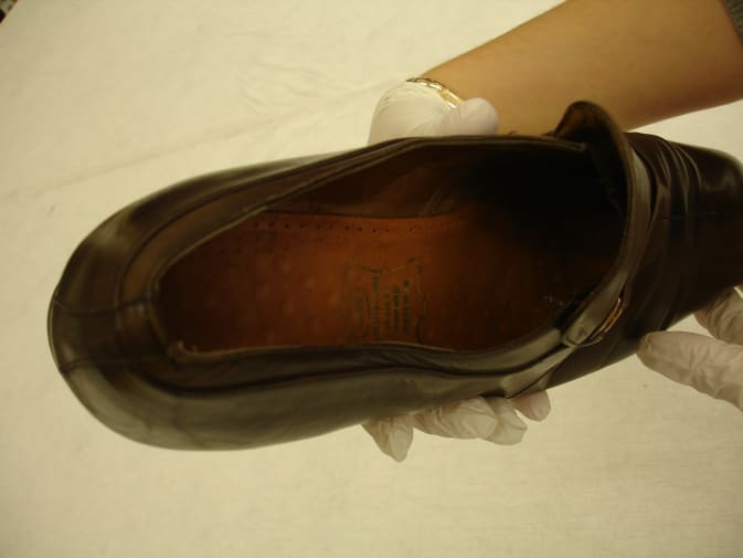 gloved hands handling old shoe