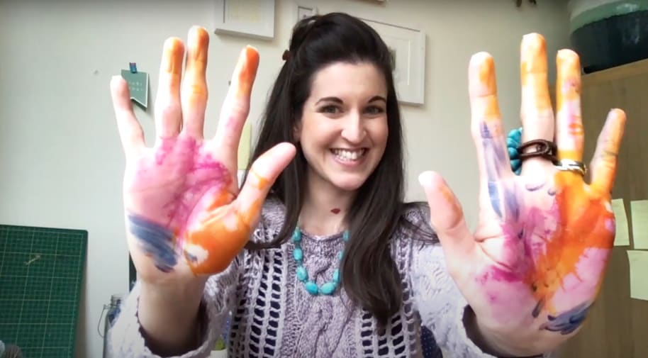 girl holding up hands covered in paint