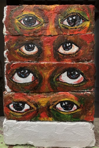 Large scale painting of 4 sets of eyes created using 4 horizontal rows of bricks stacked on top of each other, with intense colours 